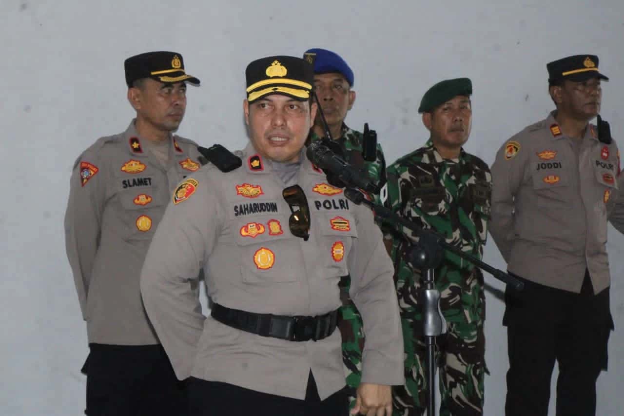 Saharuddin berbicara di depan mikrofon didampingi personel kepolisian dan TNI