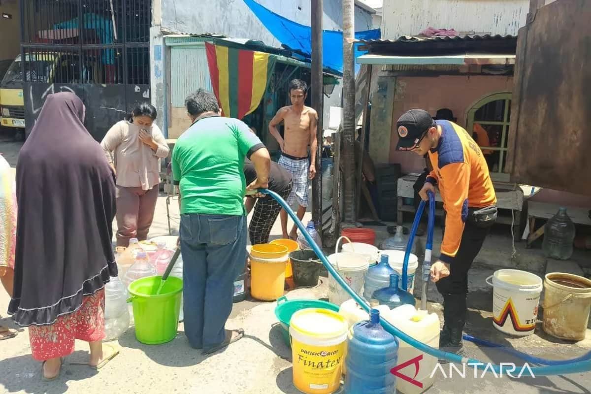 Petugas BPBD dan warga mengisi ember serta galon dengan selang air di permukiman Makassar