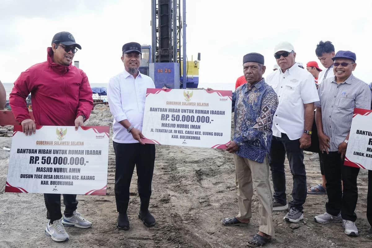 Gubernur Sulsel bersama penerima memegang papan bantuan hibah rumah ibadah di Bulukumba