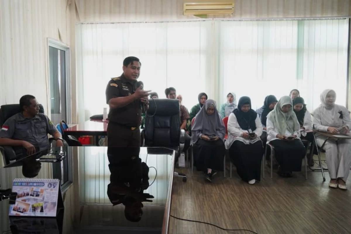 Soetarmi berdiri menjelaskan materi kepada peserta yang duduk di ruang pertemuan