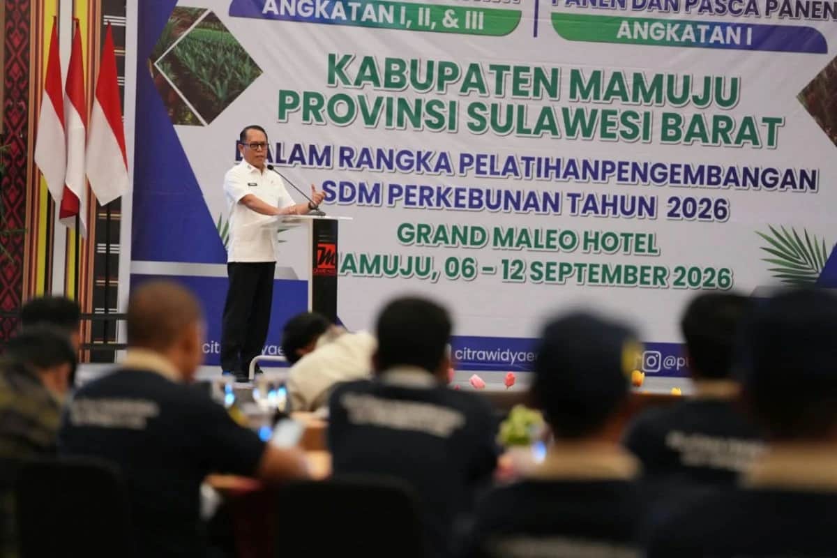Seorang pejabat berbaju putih berbicara di podium di depan peserta pelatihan perkebunan