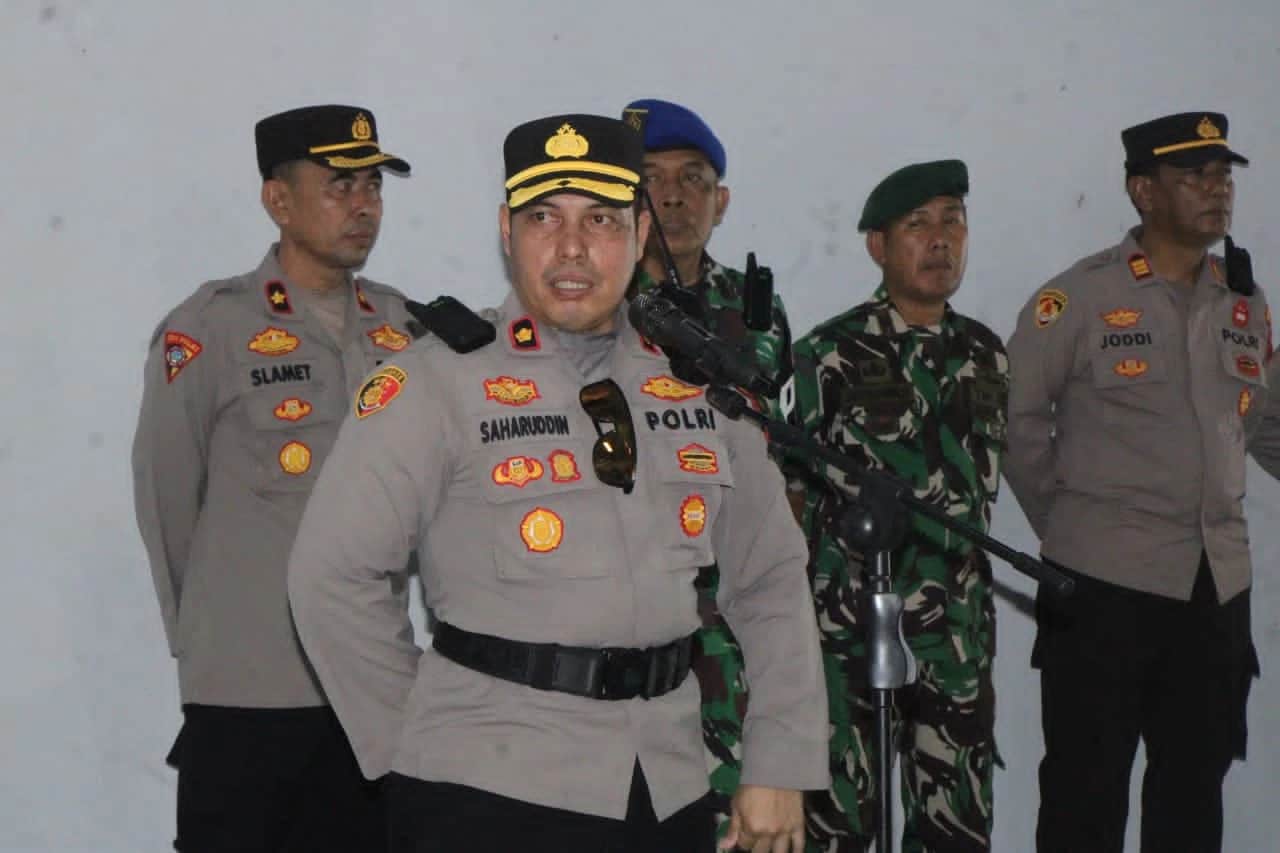 Saharuddin berbicara di depan mikrofon didampingi personel kepolisian dan TNI