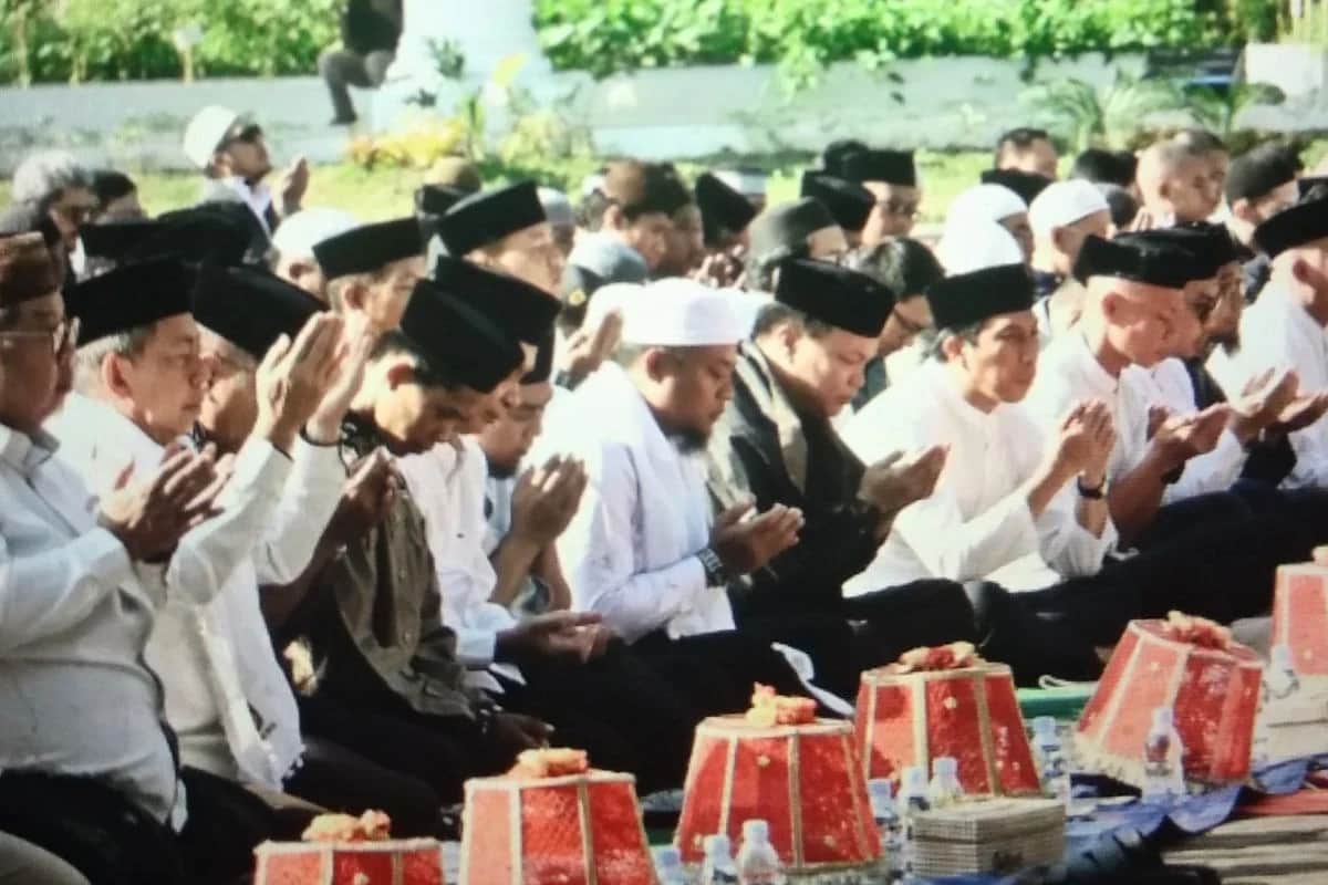 Jemaah duduk berbaris dengan tangan menengadah saat berdoa bersama