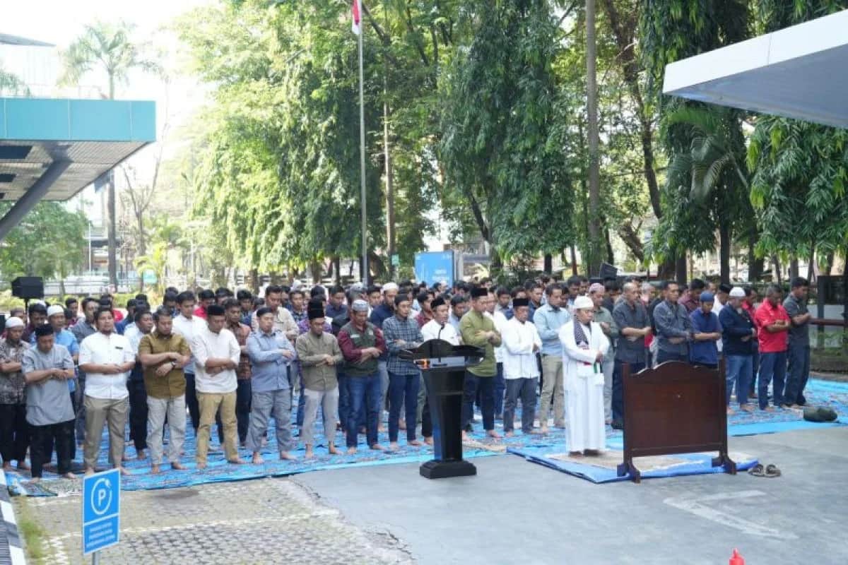 Jemaah salat berdiri berjajar di halaman kantor PLN dengan imam di barisan depan
