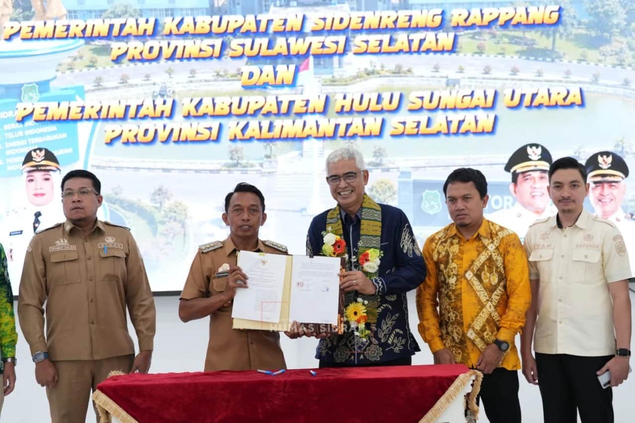 Pejabat Sidrap dan Hulu Sungai Utara memperlihatkan dokumen kesepahaman di depan latar kedua pemerintah kabupaten