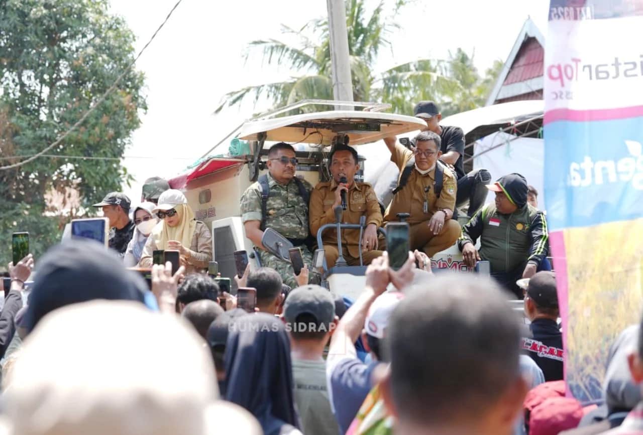 Syaharuddin Alrif berbicara melalui mikrofon di atas mesin panen di hadapan warga