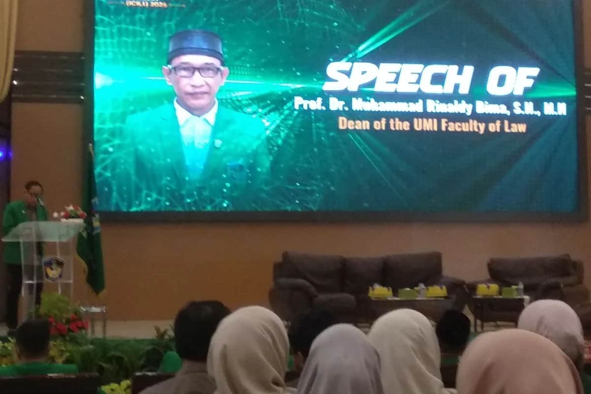 Pembicara di podium konferensi UMI dengan layar sambutan dekan dan peserta yang duduk di auditorium