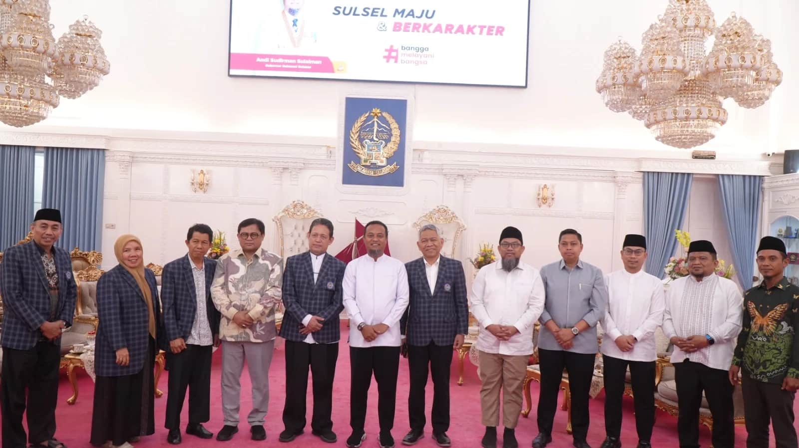 Rombongan Unismuh dan Gubernur Sulsel berfoto di ruang pertemuan dengan lambang Sulawesi Selatan