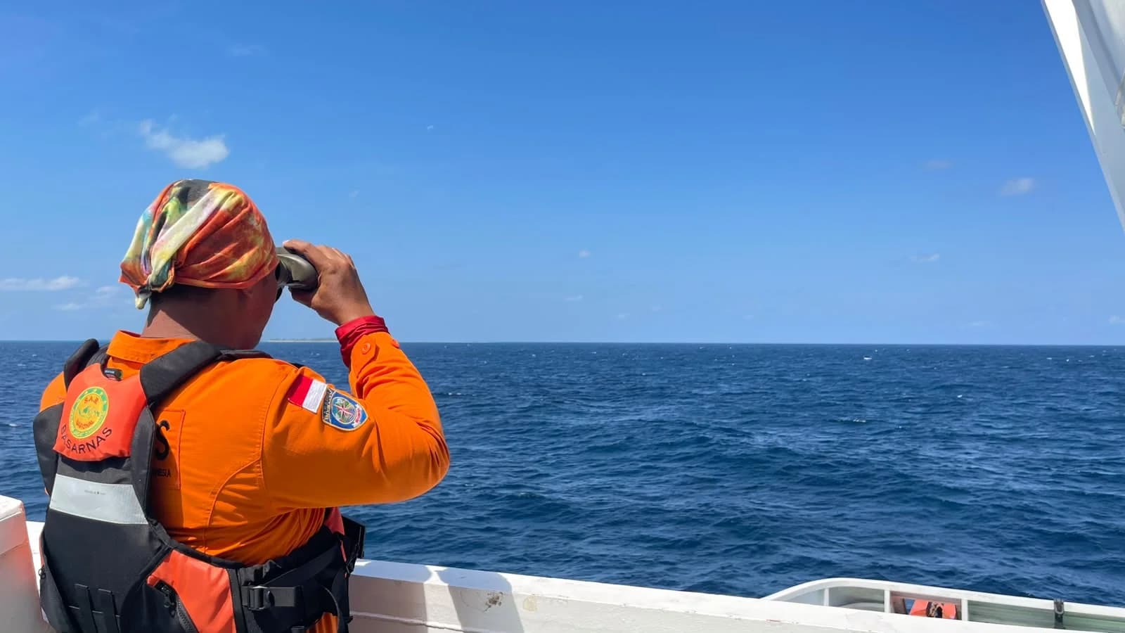 Petugas Basarnas mengamati perairan melalui teropong dari kapal pencarian
